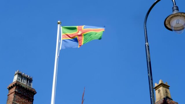The flag of the County of Lincolnshire in the East Midlands of England blowing in the wind against an azure blue sky