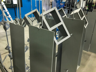 Powder coating line. Metal panels are suspended on an overhead conveyor line. Painting products in...