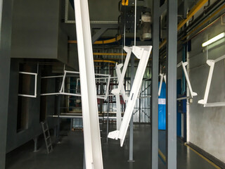 Powder coating line. Metal panels are suspended on an overhead conveyor line. Painting products in...