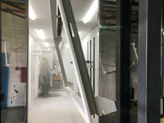 Powder coating line. Metal panels are suspended on an overhead conveyor line. Painting products in...