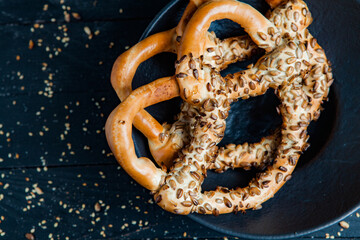 Fresh prepared homemade soft pretzels. Different types of baked bagels with seeds on a black background.