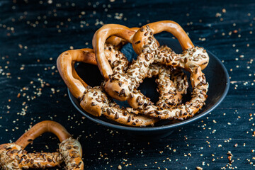 Fresh prepared homemade soft pretzels. Different types of baked bagels with seeds on a black background.