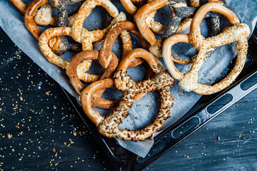 Fresh prepared homemade soft pretzels. Different types of baked bagels with seeds on a black background.
