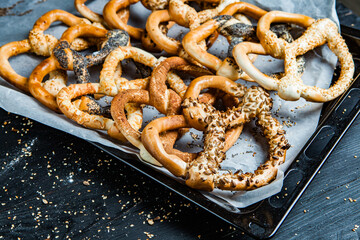 Fresh prepared homemade soft pretzels. Different types of baked bagels with seeds on a black background.