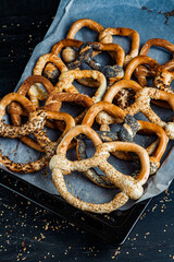 Fresh prepared homemade soft pretzels. Different types of baked bagels with seeds on a black background.