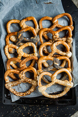 Fresh prepared homemade soft pretzels. Different types of baked bagels with seeds on a black background.