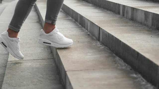Stairs walk. Outdoor run. Sporty shoes. Closeup of training woman runner feet in athletic sneakers jogging climbing on street step.