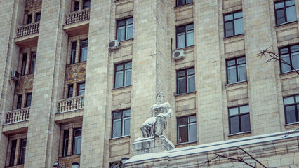 Statue of a man against the backdrop of a multi-storey building, photo during the day