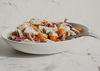 Tofu salad with yellow and red cherry tomatos and noodle in white bowl