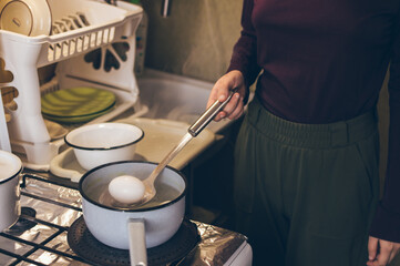Cooking eggs in enameled ladle for coloring for Easter