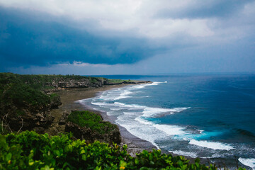 Obraz premium Storm rolls in over ocean and tropical island with waves and clouds