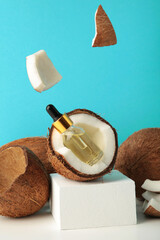 Bottle of oil in coconut with flying pieces on blue background