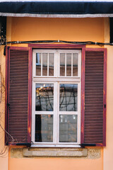 Fototapeta premium Red old wooden open shutters on the facade of the house. Vintage window.