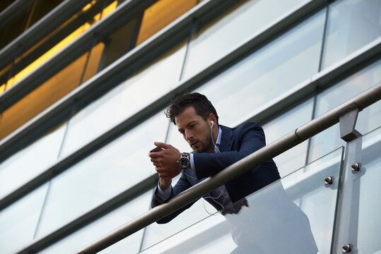 Business man standing on a balcony in the city centre at dawn