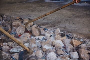 Stones heating in a well to cook curanto. Shovel, fire, smoke and rocks. Typical food of the...