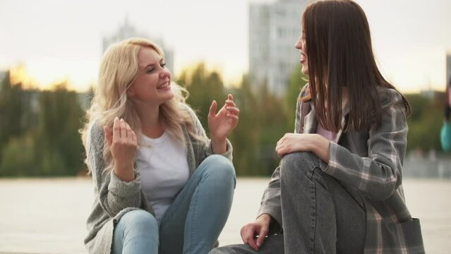 Friendship leisure. Happy talk. Weekend getaway. Joyful optimistic laughing young women friends chilling outdoors together at city street.