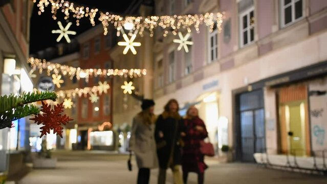 Beautiful Christmas decorations, blurred lights and people walking on the street in the city center of Graz, Steiermark, Austria, at night. Selective focus