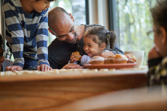 Happy father and daughter eating muffin at dining table
