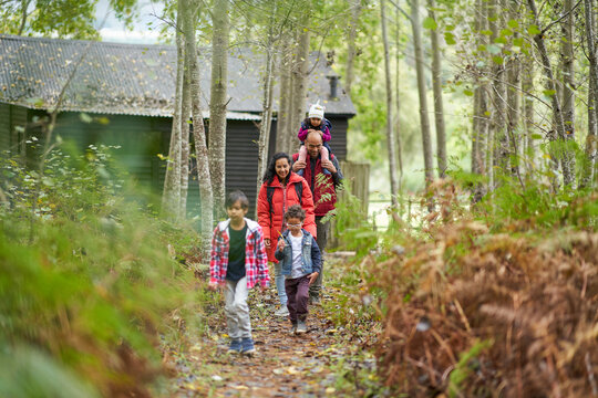 Family hiking on trail in woods outside cabin