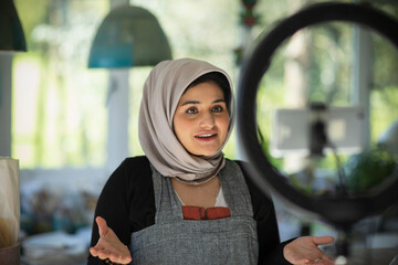 Young female influencer in hijab vlogging in studio