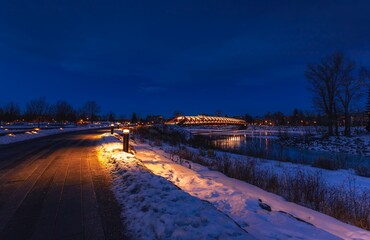 Obraz premium Illuminated Walkway By A Snowy Peace Bridge