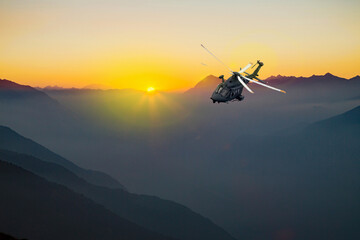 Fototapeta na wymiar military helicopter flying over the alps at sunset