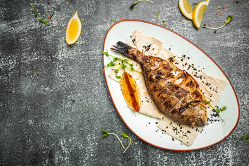 Delicious Grilled dorado fish with lemon and parsley. Whole Bbq sea bream baked. Dorado grill. Ketogenic, keto or paleo diet lunch, Healthy food trend. Top view