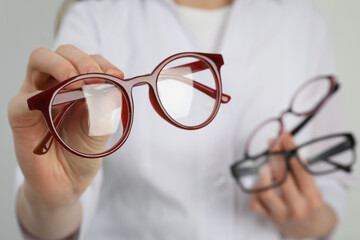 Woman with different glasses on light background, closeup