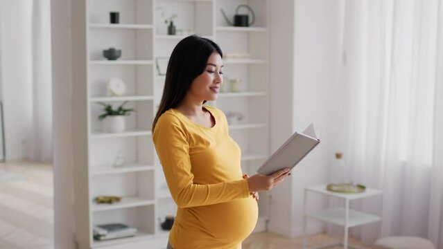 Pregnancy Leisure. Beautiful Pregnant Asian Woman Reading Book At Home