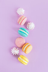 Tasty french macaroons on a violet pastel background.