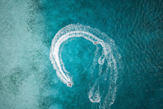 Aerial Top Down View Of People Circling Around On Jet skis Over Blue Ocean Waves In Male, Maldives.