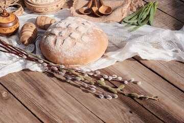 A traditional set of bread, loaves and other wooden accessories. Round white rye bread. Wooden background. Wheat, willow branches, Easter holiday