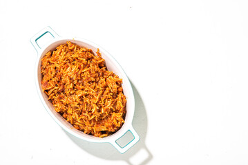 Jollof rice in a dish on a white background. Traditional Nigerian food made from rice, tomatoes and spices. Top view, place for text.