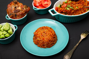 Jollof rice on a plate. Rice with tomatoes, onions, spices. Traditional national Nigerian food. Dark background.