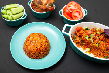 Jollof rice on a plate. Rice with tomatoes, onions, spices. Traditional national Nigerian food. Dark background.