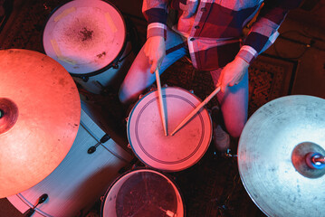From above of crop faceless male musician in casual wear playing drums while performing song during...