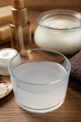 Homemade natural rice water and cosmetic products on wooden table, closeup