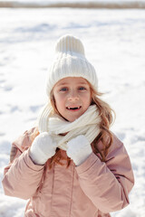 Funny little blonde girl of 7 years old in casual winter clothes posing outside in snowy weather . The concept of a child's lifestyle. Layout of the copy space.