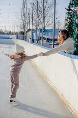 Funny little blonde girl of 7 years old in casual clothes posing on a skating rink in skates. The...