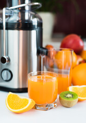 Multivitamin fruit juice in a glass on the table in the kitchen. Making healthy and tasty juices at home. Selective focus. Close-up.