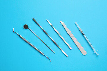 Set of different dentist's tools and syringe on light blue background, flat lay