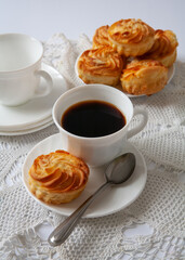 On the table are a cup of coffee and cakes. On white background. Selective focus.