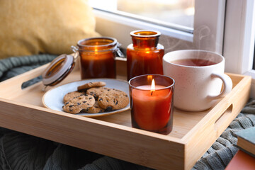 Breakfast tray with burning candles near window indoors
