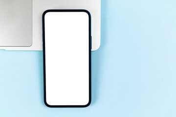 Flat lay smartphone mockup, office desktop with laptop, bright blue background. Top view, copy space photo