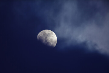 Moon behind dark blue clouds