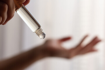 Closeup of a woman using rollerball perfume on her wrist.