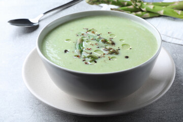 Delicious asparagus soup served on light grey table, closeup