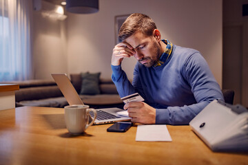 A worry man looking at his credit card with no invoice and having troubles with payment while...