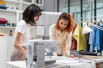 Obraz premium Asian two tailor woman working to design clothes in tailoring atelier. 
