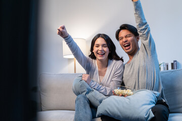 Asian new marriage couple watching football sport game on television. 